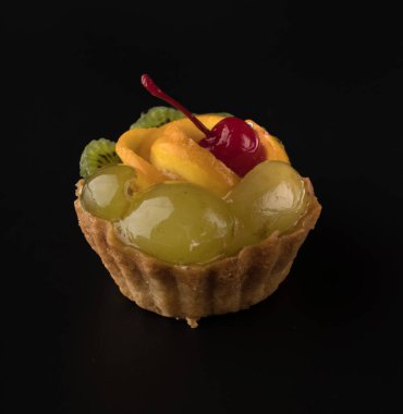 Kiraz üzümlü, kivili ve narenciyeli meyveli, siyah arka planda meyveli pasta.