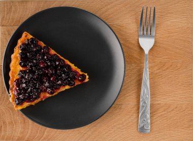 Kesilmiş havuçlu kek. Üstünde frenk üzümü ve ahşap bir tahta çatal var.