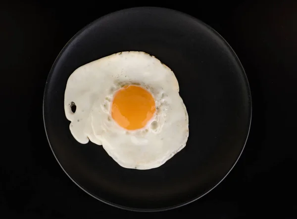 Fried Egg Lies Black Plate Black Background Isolated — Stock Photo, Image