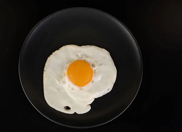 Fried Egg Lies Black Plate Black Background Isolated — Stock Photo, Image