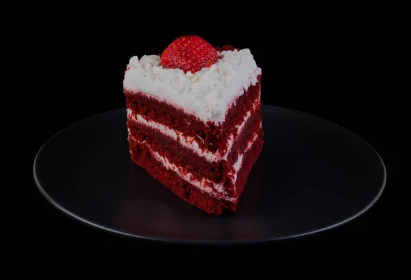Piece of cake covered with protein cream and strawberries on a black plate and black background isolated — Zdjęcie stockowe