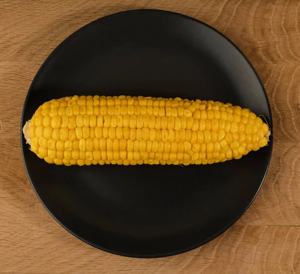 成熟的玉米放在一块黑色的盘子里 放在一块木板上 上面有一层卷心菜皮 — 图库照片