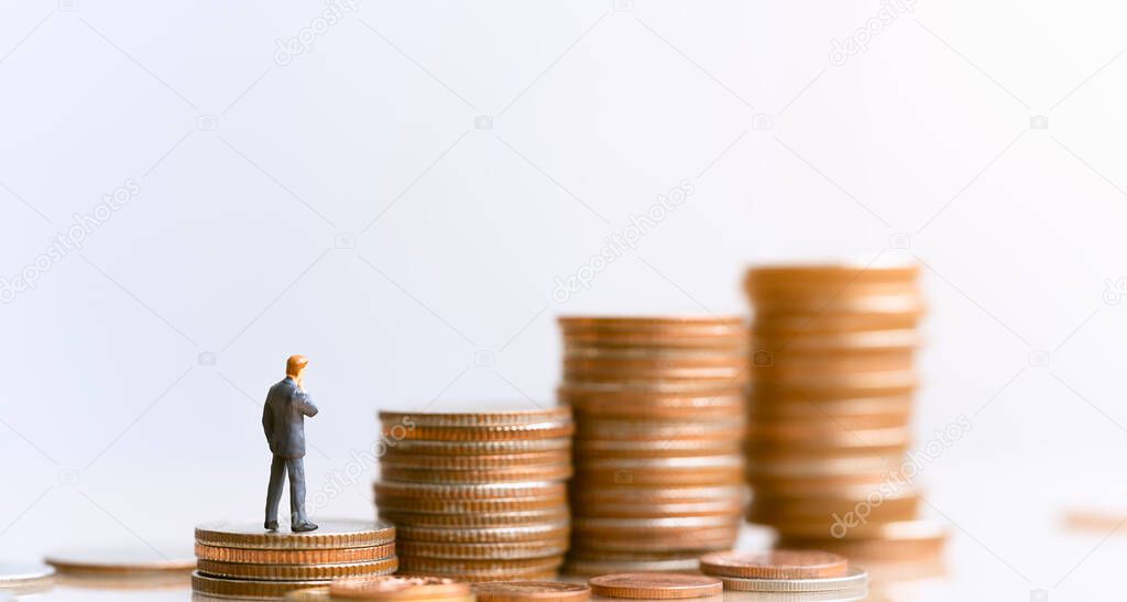 Miniature people: Businessman standing on coin stack.  Plan investment strategies and goals. Inequality and social class. Income and economic inequality concept.