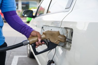 Hand hold Fuel nozzle to add fuel in car at filling station clipart