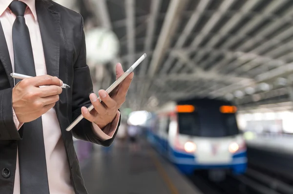 Geschäftsmann mit dem Tablet auf abstrakt verschwommenem Foto des Himmelsbahnhofs mit Menschen im Hintergrund — Stockfoto