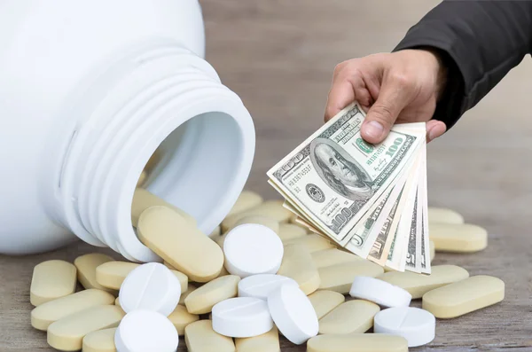 Businessman Hand with usd dollar money for Many Pills and vitamin on wood background — Stock Photo, Image