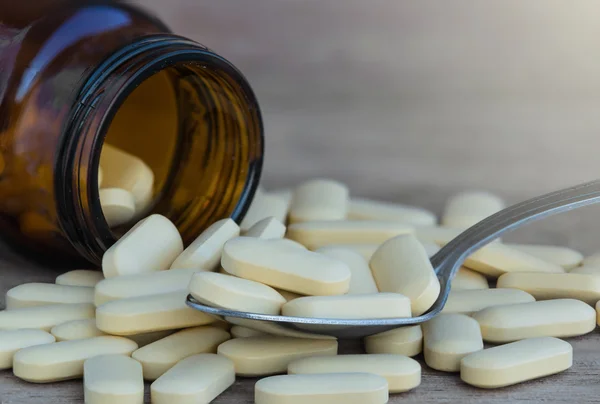 Prášky nebo vitaminu v lahvích medicíny na pozadí lžíce — Stock fotografie