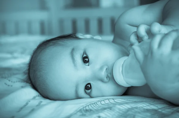 Aziatische baby consumptiemelk op het bed — Stockfoto