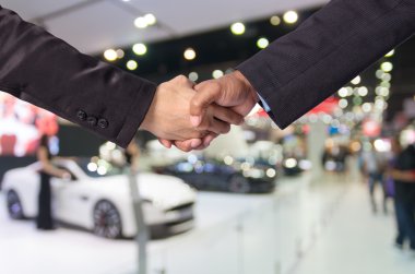 Bir işadamı ve bir iş kadını soyut bulanık fotoğraf Otomobil Fuarı arka plan arasında el sallamak