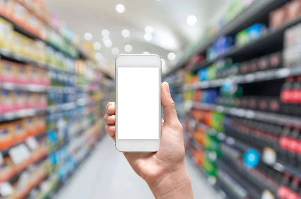 Mão feminina segurando telefone inteligente móvel no fundo de borrão do supermercado, conceito de negócio — Fotografia de Stock