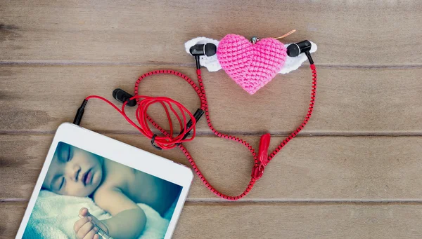 Fones de ouvido de áudio portáteis com tela de bebê asiático em comprimidos e sabão cardíaco no fundo de madeira — Fotografia de Stock