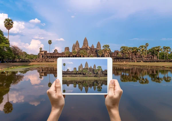 Manos femeninas sosteniendo la tableta tomando fotos Angkor Wat en Siem Reap. Camboya — Foto de Stock