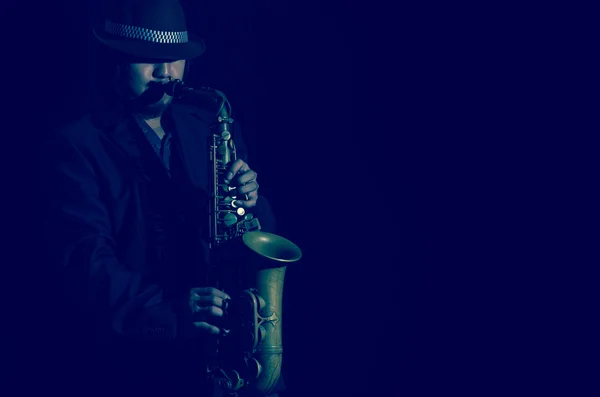 Een saxofonist in een donkere achtergrond, donker blauwe Toon — Stockfoto