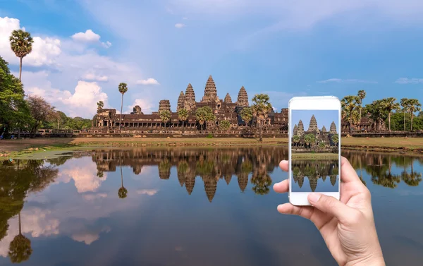 Manos femeninas sosteniendo el teléfono inteligente móvil tomando fotos Angkor Wat en Siem Reap. Camboya — Foto de Stock