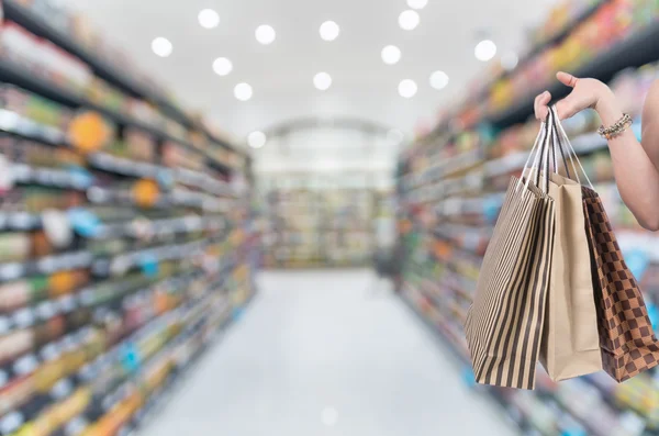 Holdingbolag shoping väskor för hand på Supermarket oskärpa bakgrund med bokeh, Diverse produkt hylla — Stockfoto