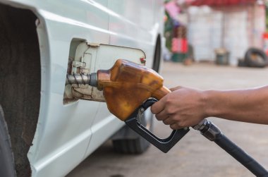 Hand hold Fuel nozzle to add fuel in car at filling station clipart