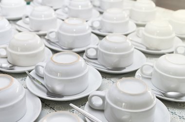 Beyaz kahve fincanı tabağı ve tabloda çay kaşığı ile birçok satır