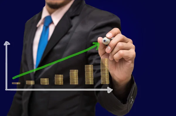 Empresario está escribiendo el gráfico de crecimiento de éxito con pilas de monedas de oro — Foto de Stock