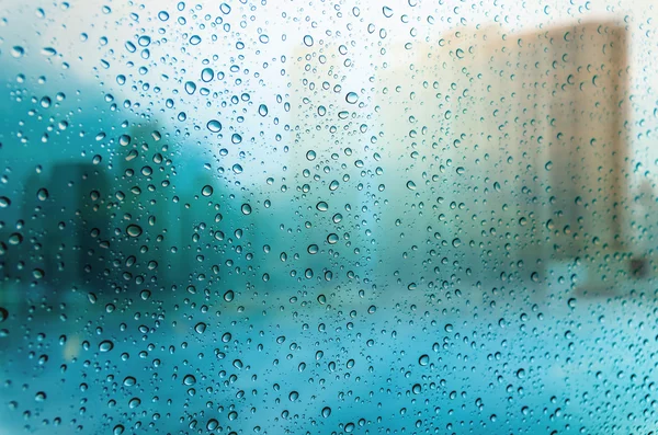 Gocce d'acqua su finestra di vetro con paesaggio urbano — Foto Stock