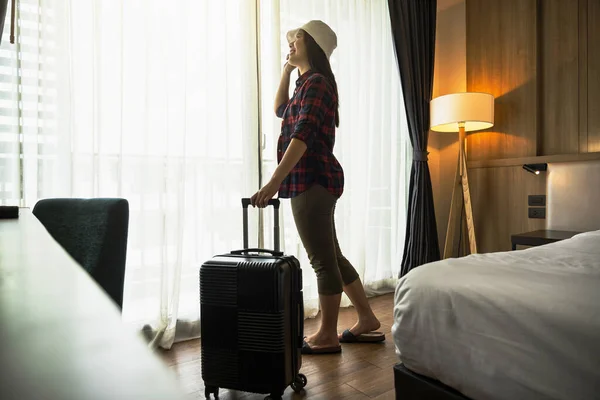 幸福アジアの旅行者の女性は 彼女の休日に旅行するときにホテルやホステルのベッドルームで荷物を持って立って 豪華なインテリアの寝室のデザイン 観光や旅行のコンセプト — ストック写真