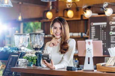 Asya Küçük işletme genç sahibi NFS teknoloji makinesini elinde tutuyor. Kahve dükkanındaki müşteri siparişlerini kontrol ve fatura ile kontrol ediyor. Küçük işletme sahibi ve girişim konseptini kontrol ediyor.