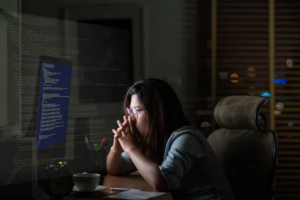 Asian Businesswoman working hard with front of computer desktop with programming source code and motion graphic over computer screen in work place at late times with exciting and serious action