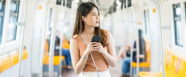 大都市 交通の概念で旅行するとき スマートフォンを使用して地下鉄の列車の外を見て 若いアジアの女性の乗客 — ストック写真