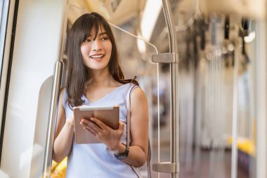 Büyük şehir, Japonca, Çince, Kore yaşam tarzı ve günlük yaşam, banliyö ve ulaşım kavramında seyahat ederken metroda teknoloji tableti ile sosyal ağı kullanan genç Asyalı kadın yolcu.