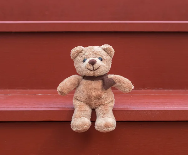 Oso TEDDY color marrón sentado en la escalera roja —  Fotos de Stock