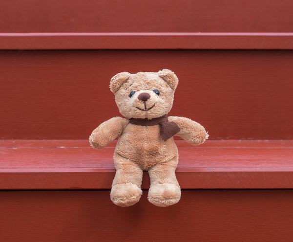 TEDDY BEAR brown color sitting on red staircase