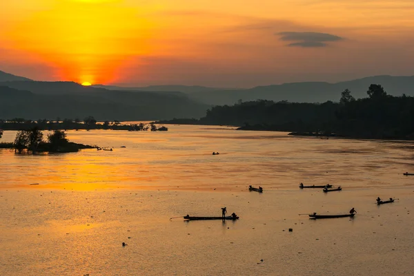 Muchos pescador remando bote de remos a la pesca con puesta de sol, silueta — Foto de Stock