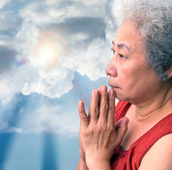 老女人用蓝色的天空和太阳光线祈祷 — 图库照片