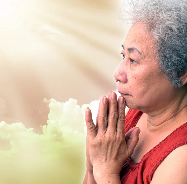 Old woman praying with sun ray