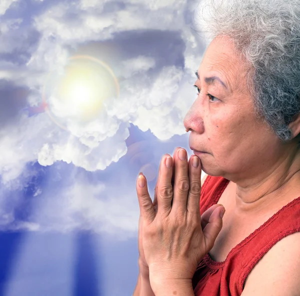 老女人用蓝色的天空和太阳光线祈祷 — 图库照片