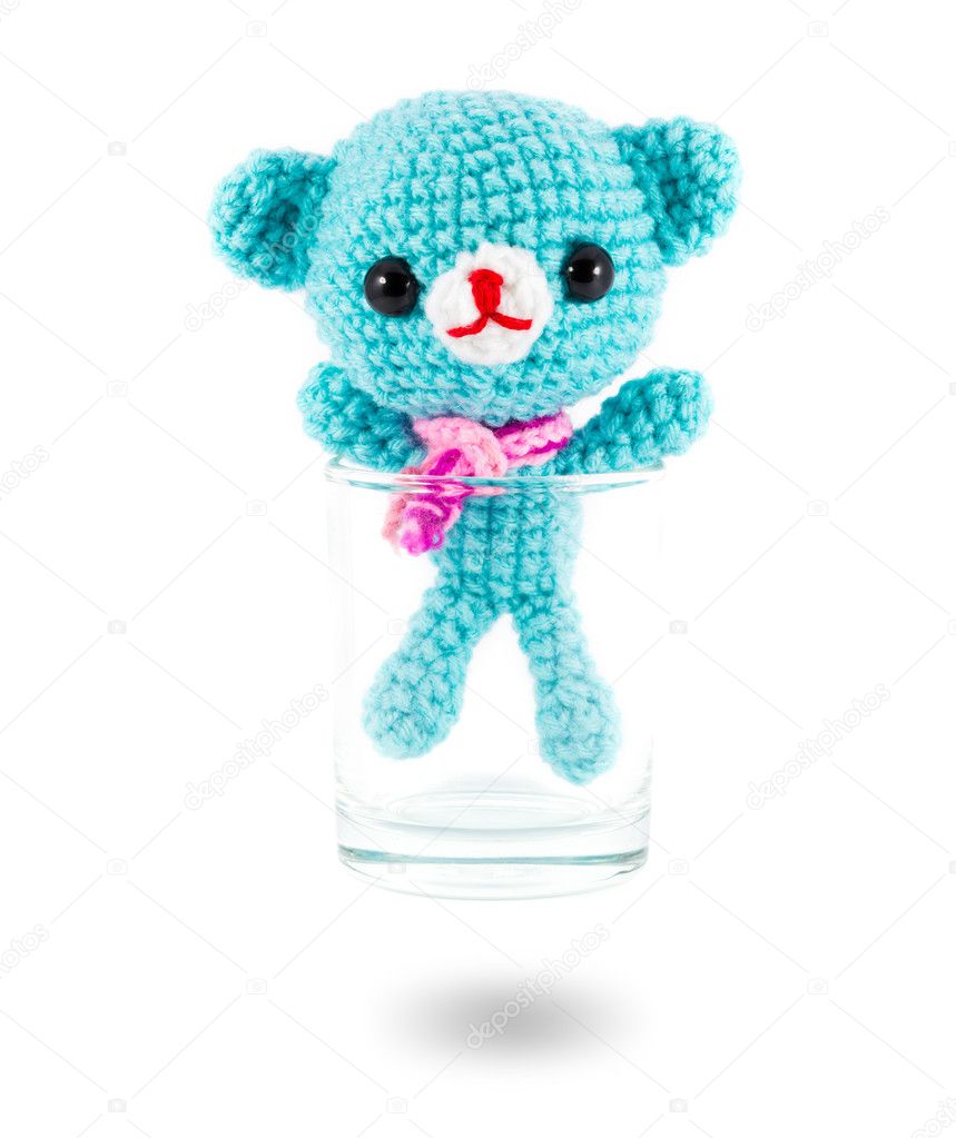 handmade crochet blue bear doll in vodka glass on white backgrou