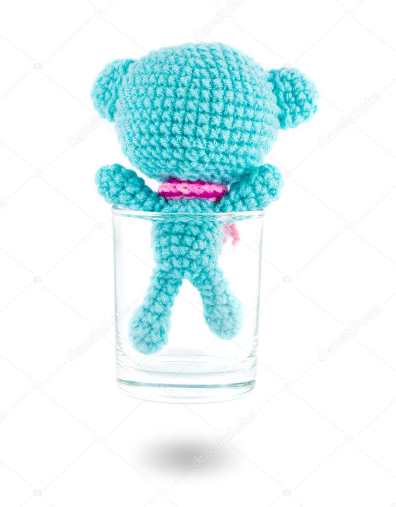 handmade crochet blue bear doll in vodka glass on white backgrou