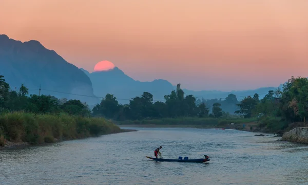 Pescador remando bote a la pesca al atardecer, vangvieng, Laos — Foto de Stock