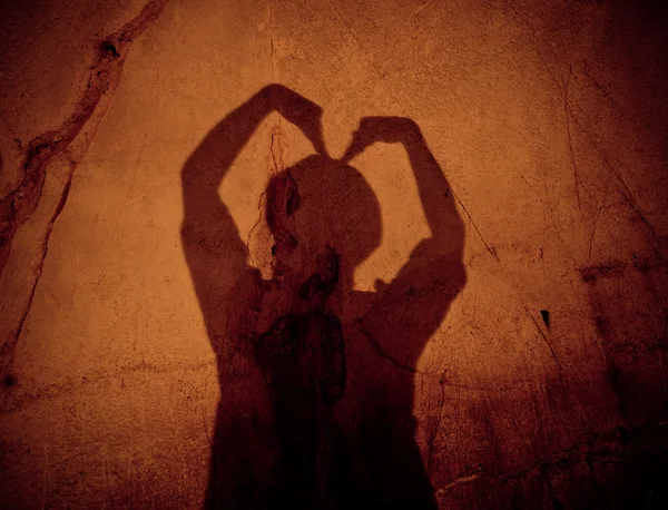 Две руки, образующие тень сердца на стене в пещере — стоковое фото
