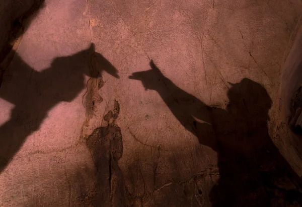 Dos manos formando una sombra de pistola en la pared de la cueva —  Fotos de Stock