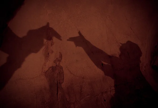 Две руки образуют тень от пистолета на стене в пещере — стоковое фото