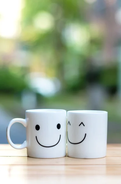 Two happy cups on wood table with bokeh, about love concept — Stock Photo, Image