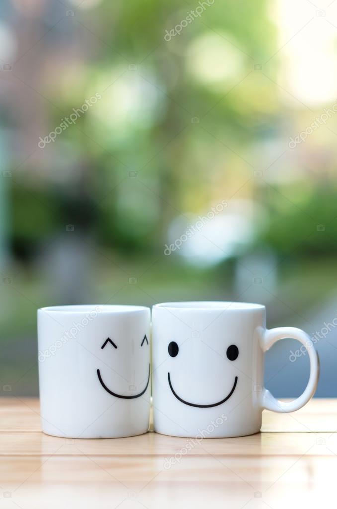 Two happy cups on wood table with bokeh, about love concept