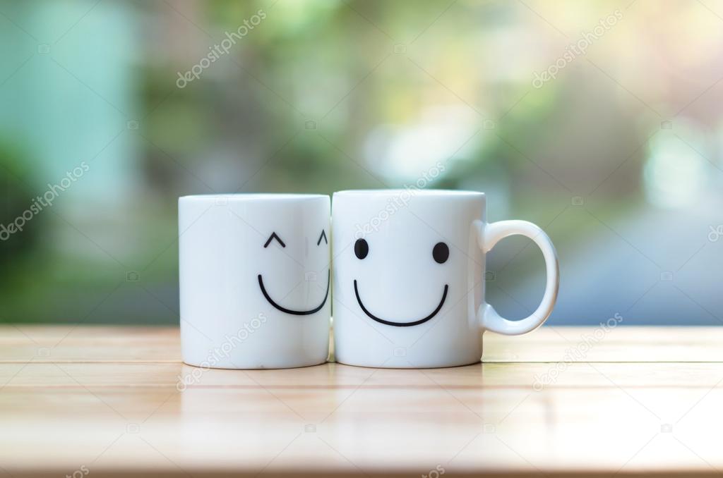Two happy cups on wood table with bokeh, about love concept