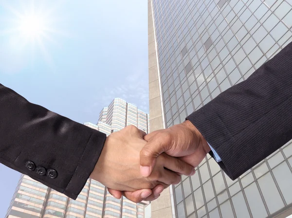 Stringere la mano tra un uomo d'affari su sfondo edificio in vetro moderno — Foto Stock