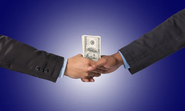 Hand shake between a businessman with dollar money on dark blue — Stock Photo, Image