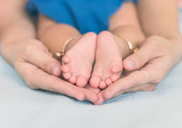 Детские ножки на материнской руке — стоковое фото