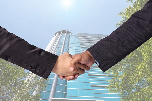 Agitar la mano entre un hombre de negocios en el edificio de vidrio moderno backgr —  Fotos de Stock