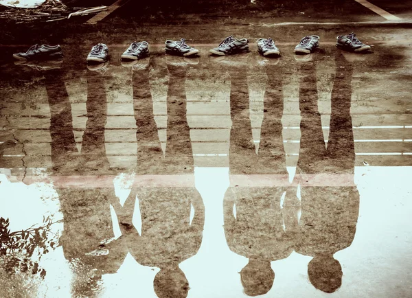 Четыре человека отражение в воде после дождя, двойное воздействие тени — стоковое фото