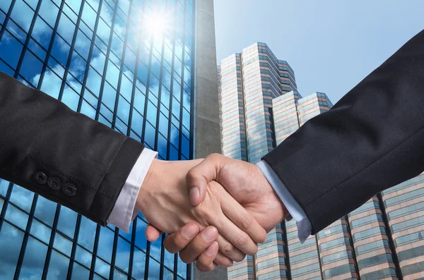 Hand shake between a businessman on Modern glass building background — Stock Photo, Image