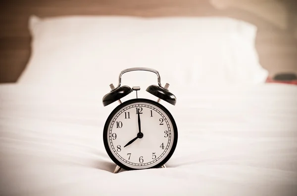 Reloj despertador vintage en la cama — Foto de Stock